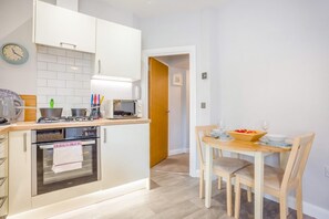Eine kleine Küche mit Mikrowelle, Herd und Backofen, die in einen Essbereich mit Tisch und Stühlen übergeht.