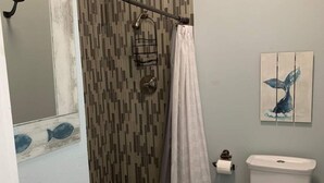 A bathroom with a white sink, a toilet, a shower curtain, and a wall-mounted towel rack. - Whale of a Time offers a thoughtfully designed space (Galveston)