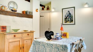 Un comedor con una mesa lista para dos, un aparador con cajones, un espejo y un cuadro en la pared.