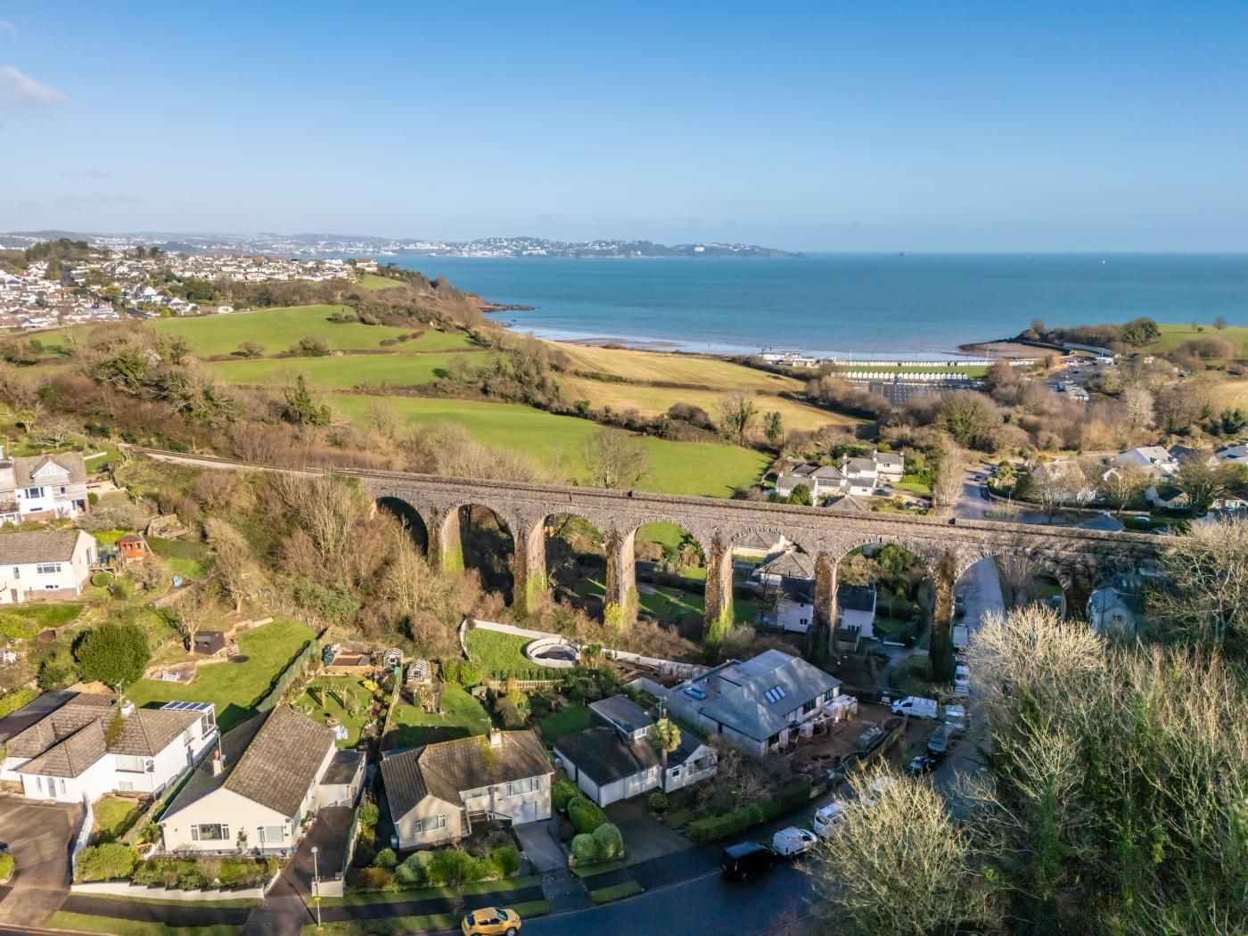 A coastal residential area with houses, a bridge, and a view of the sea.