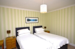 Ein Doppelzimmer mit zwei Einzelbetten, einem gerahmten Bild an der Wand und einer Hängelampe.