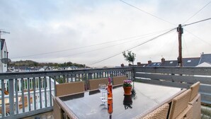 A balcony with wicker furniture, a glass table, and a potted plant. - 3 Bed in Mumbles (oc-hh1223) (The Mumbles)