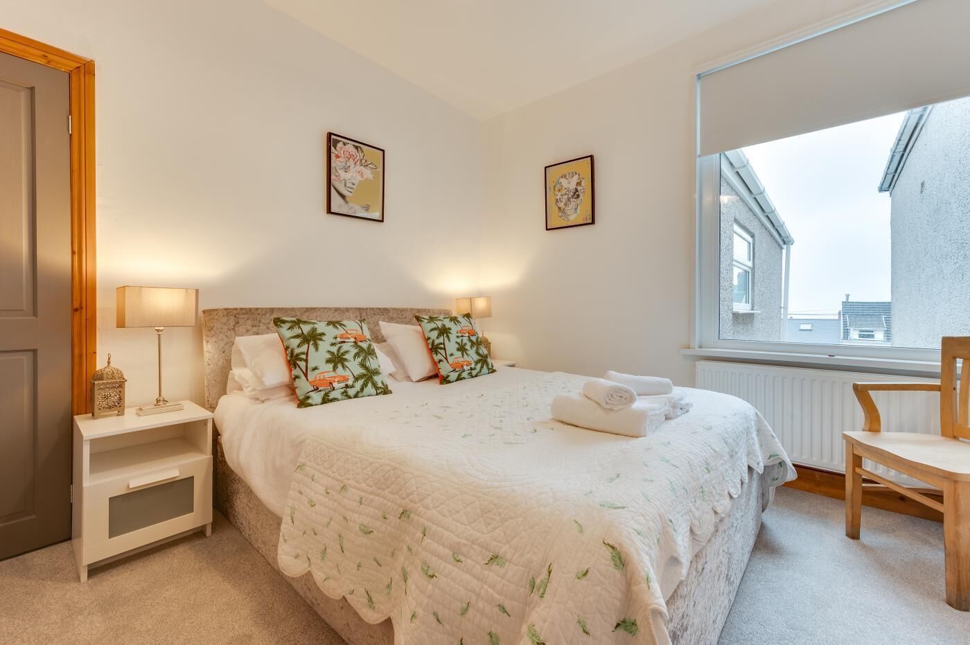 Een slaapkamer met een bed, nachtkastjes, een stoel en een raam met uitzicht.