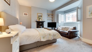 A bedroom with a bed, bedside table, lamp, TV, and a window with blinds. - 3 Bed in Mumbles (oc-hh1223) (The Mumbles)