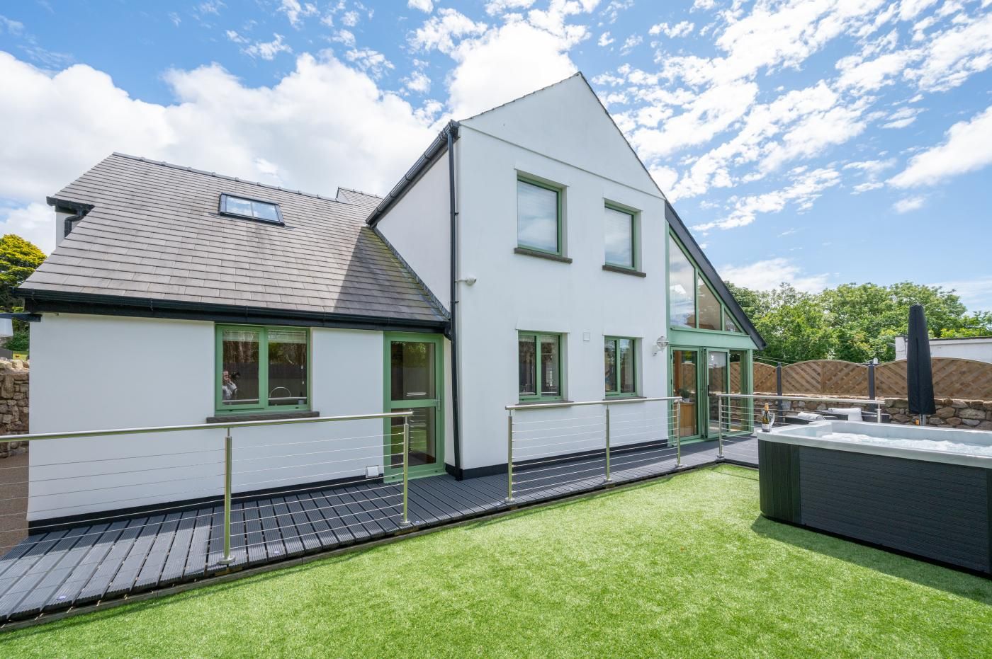 Et moderne hus med to etager, fladt tag, store vinduer og en lille balkon.