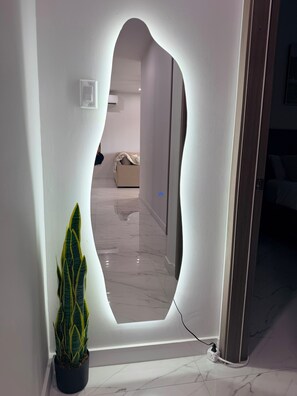 Un couloir orné d’une arche murale originale, avec une plante en pot et un aperçu d’une pièce où l’on aperçoit un canapé.