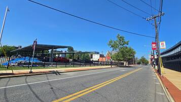A clear road with a double yellow line, a covered parking area, and a building with a red roof.