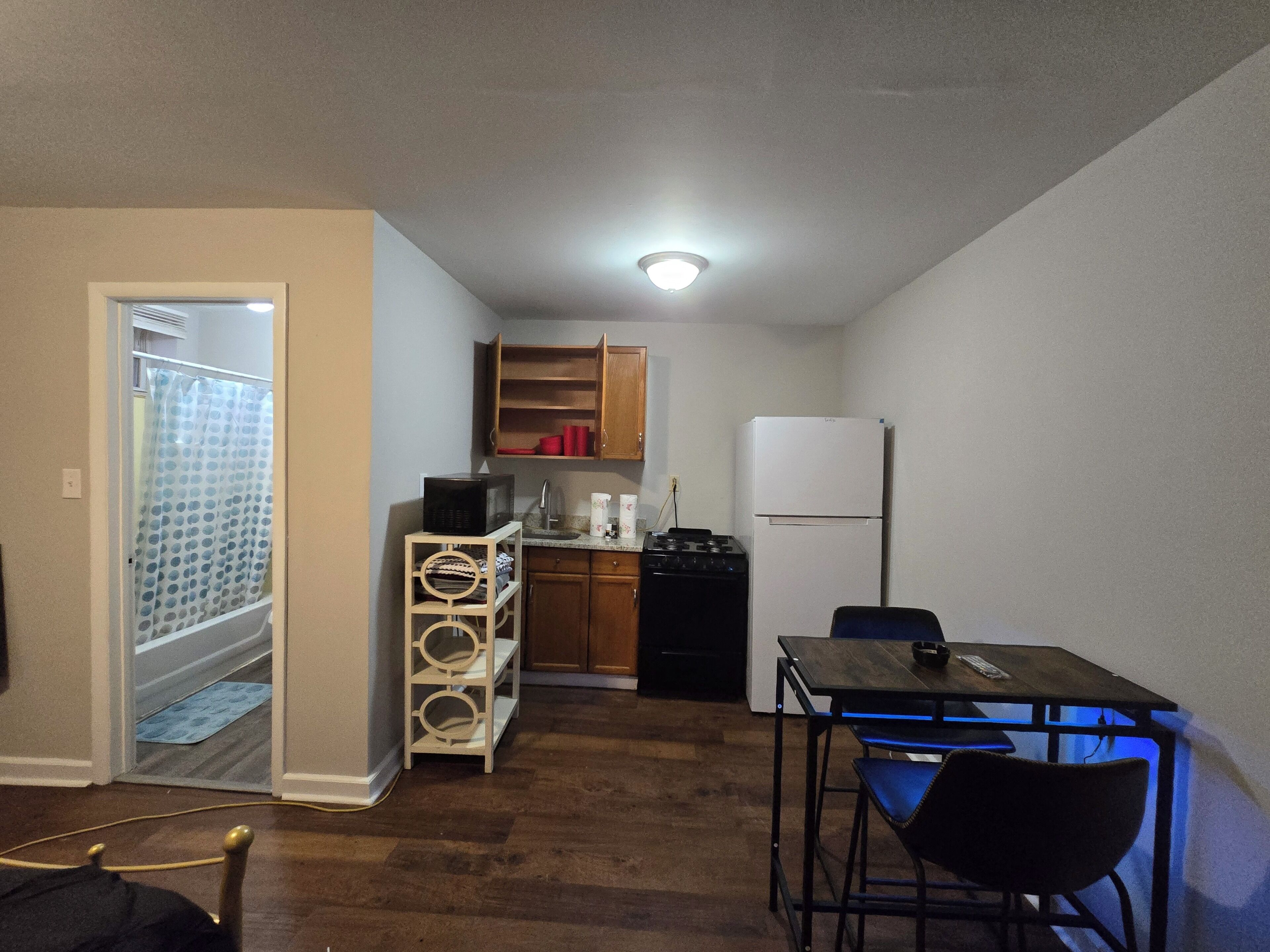 A compact kitchen with a refrigerator, stove, microwave, and wooden cabinets.