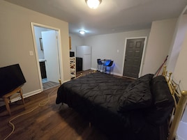 Un dormitorio con una cama, un escritorio con sillas, un televisor y una puerta.