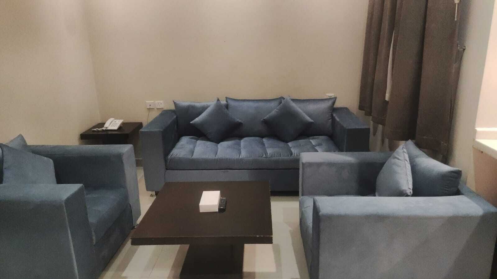 En stue med en sofasæt, et sofabord og et sidebord med en telefon.