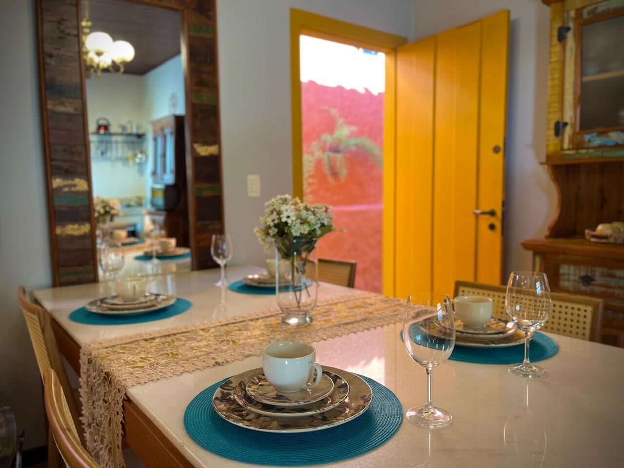 A dining table set with plates, glasses, and a vase of flowers.
