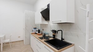 Une cuisine moderne avec des meubles blancs, un évier noir et un sol à motifs en chevrons.
