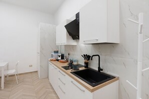 Eine moderne Küche mit weißen Schränken, einem schwarzen Spülbecken und einem Fischgrätparkett.
