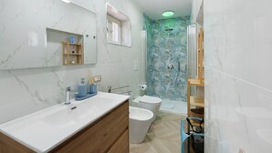 Une salle de bain avec un meuble-lavabo en marbre, des toilettes, une douche avec une porte en verre et un miroir avec une étagère au-dessus.