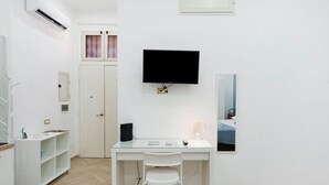 Une chambre d’hôtel équipée d’un bureau, d’une chaise, d’une télévision et d’un lit recouvert d’une courtepointe bleue.