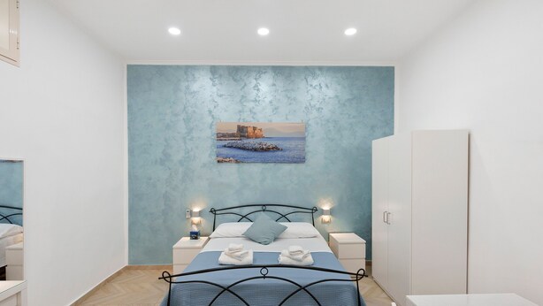 Une chambre à coucher avec un lit, des tables de chevet, une armoire et un tableau accroché au mur.