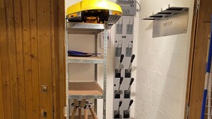 A compact storage area with shelves, a small stool, and a trash bin. - Renovated Studio for 4 People Les Menuires – Ski-in/Ski-out with Direct Access to the Slopes – Brelin (Les Belleville)