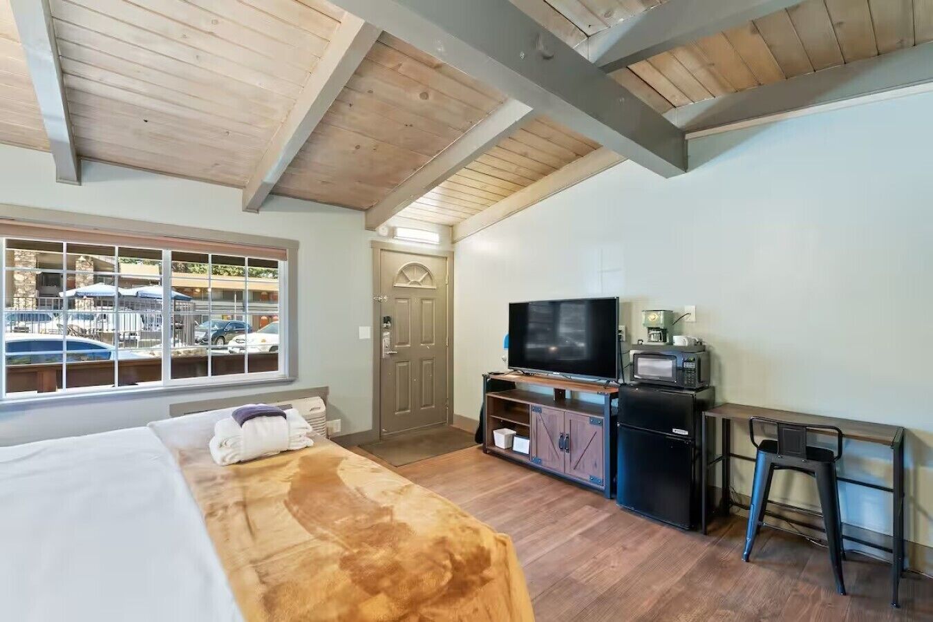 A room with a bed, a TV, a coffee machine, and a view of a marina through a window.