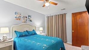 A bedroom with a bed, two bedside tables with lamps, a ceiling fan, a door, and curtains. - 4 bed 2 bath townhome walking distance from the beach! (Panama City Beach)