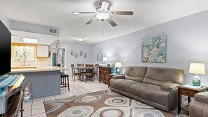 A living room with a sofa, a TV, a ceiling fan, and a dining area with chairs and a table. - 4 bed 2 bath townhome walking distance from the beach! (Panama City Beach)