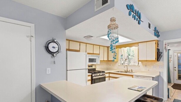 A kitchen with a central island, a clock, and a decorative hanging light. - 4 bed 2 bath townhome walking distance from the beach! (Panama City Beach)