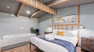 A modern bedroom with a large bed, a built-in bathtub, and a wooden ceiling structure.