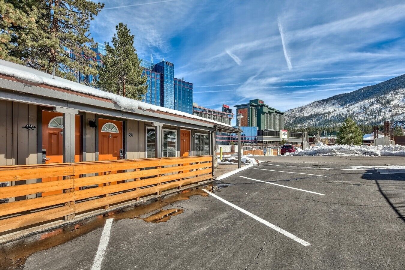 A building with a covered outdoor seating area, a parking lot, and a mountainous backdrop.