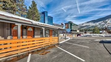 A building with a covered outdoor seating area, a parking lot, and a mountainous backdrop.