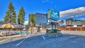 A Blue Jay Lodge sign, a fenced pool area, and a parking lot with a building in the background.
