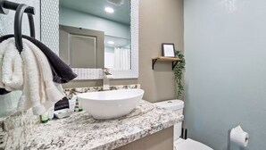 A bathroom with a white sink, marble countertop, and a toilet.