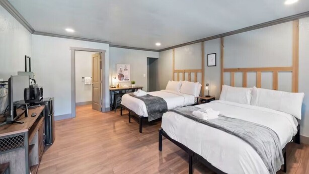 A hotel room with two beds, a desk with a computer, and a TV.