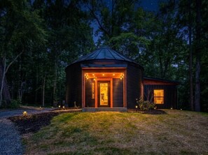 A wooden cabin with a welcoming entrance, surrounded by a forest.