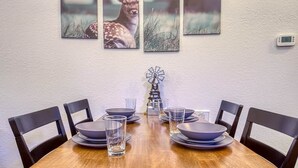 Una mesa de comedor con un reloj, seis sillas y una decoración con forma de molino.