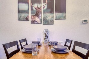 A dining table with a clock, six chairs, and a windmill decoration.