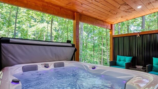 Un jacuzzi con techo de madera y vista a un bosque.