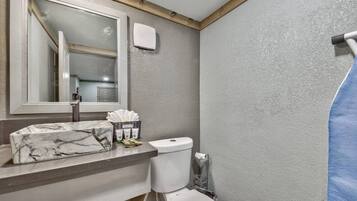 Une salle de bain avec un lavabo en marbre, des toilettes, un rideau de douche et un miroir.