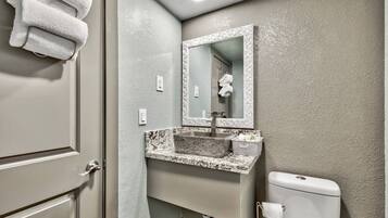 A bathroom with a marble sink, a toilet, and a mirror with an ornate frame.