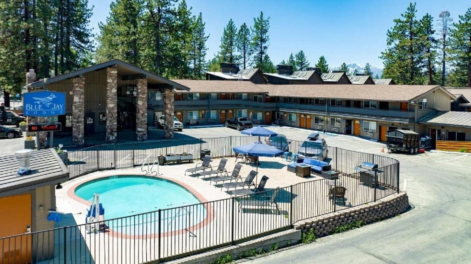 Un espace piscine avec des chaises longues et des parasols, un bâtiment principal et une vue imprenable sur les montagnes.
