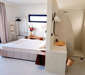 A modern bedroom with a large bed, a bedside table with a vase, a mirror, and a shower area. - Syros House - Suite: Slow Living by the Sea, Private Terrace, Ocean Views (Azolimnos)