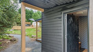 Ein modernes Gebäude mit dunkler Fassade, einer Holzveranda und einem Kiesweg, der zu einer Tür führt.