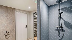 Ein modernes Badezimmer mit Dusche, Handtuchhalter und einem Holzschemel.