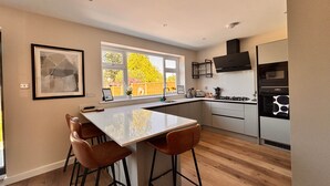 A modern kitchen with a central island, bar stools, and a view of the outside.