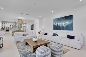 A modern living room with a white sofa set, a wooden coffee table, and striped ottomans. - Gulfside Oasis a Dream on the Gulf (Marathon)