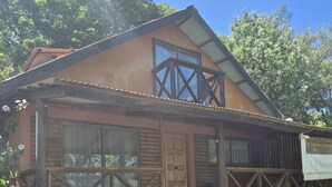 Una casa de madera con porche, ventanas grandes y techo de metal.