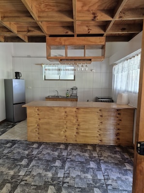 Una cocina con una isla de madera, un refrigerador y un ventanal con cortinas.
