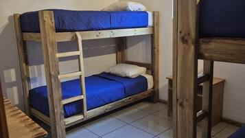 A bunk bed room with a wooden ladder, a small table, and a window.