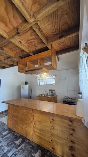 A kitchen with wooden beams, a wooden counter, a refrigerator, and a stove.