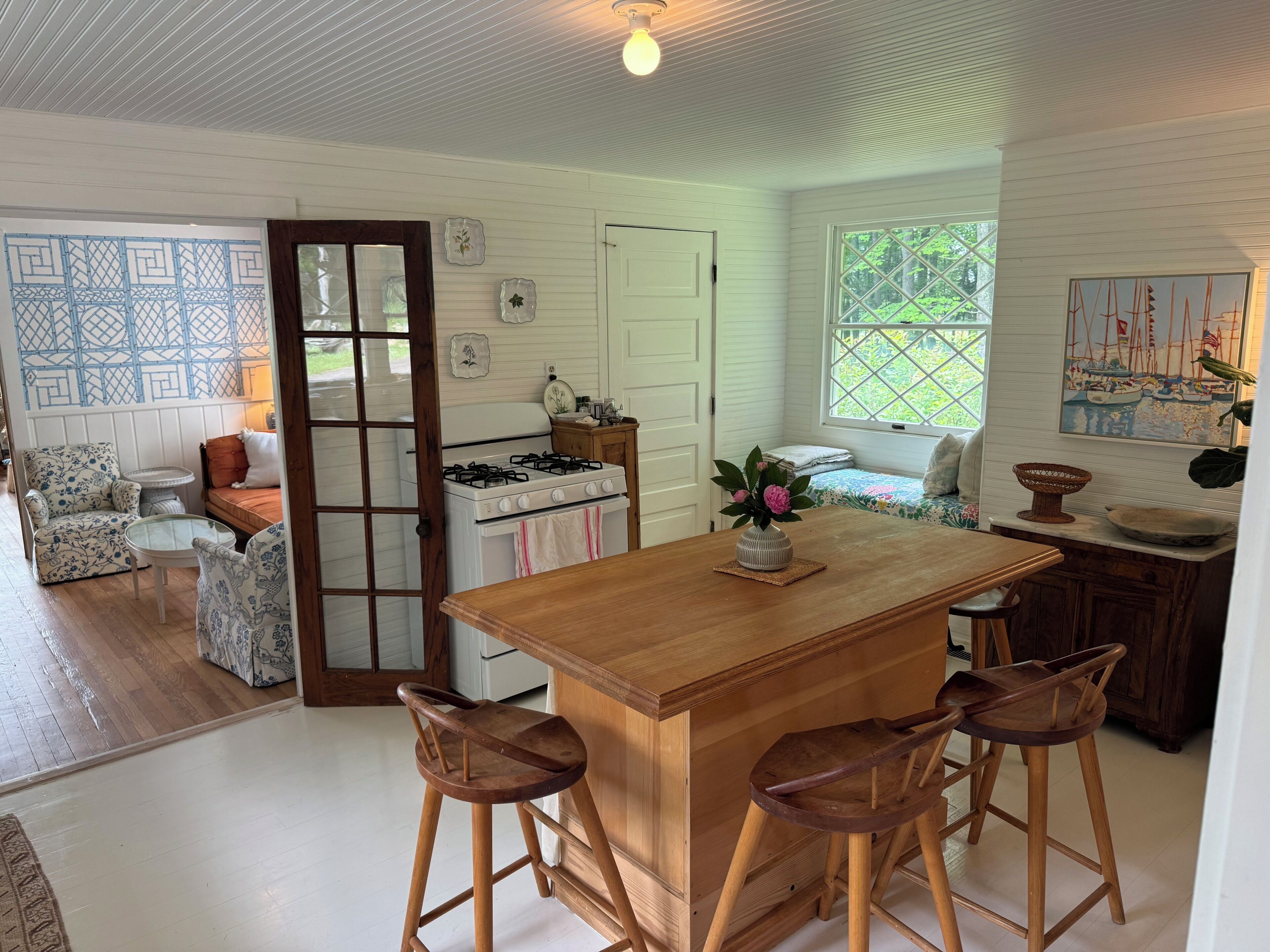 Una cocina con una isla central, taburetes de bar, estufa y una mesa de comedor.