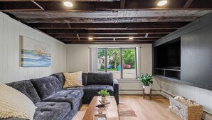 Un salon comprenant un canapé d’angle, une table basse en bois, un téléviseur et une vue sur l’extérieur.