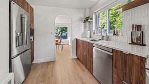 Une cuisine moderne avec des meubles en bois, des appareils électroménagers en acier inoxydable et une vue sur l’extérieur.